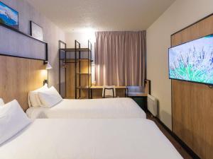 a hotel room with two beds and a flat screen tv at ibis Grenoble Gare in Grenoble