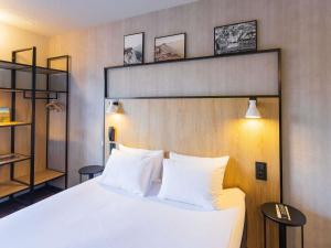 a bedroom with a large bed with white pillows at ibis Grenoble Gare in Grenoble