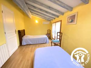 two beds in a room with yellow walls and wooden floors at La cave de jean in Gardie