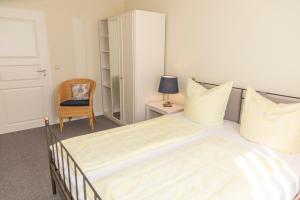 una camera da letto bianca con un letto e una sedia di Gästehaus Pfeiffer a Bad Mergentheim