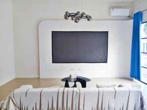un salon avec une télévision à écran plat sur un mur dans l'établissement 闲肆民宿, à Sanya