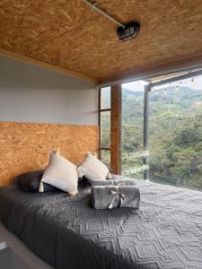 een slaapkamer met een groot bed met een groot raam bij Nakawe Guatape in Guatapé