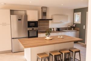 a kitchen with a counter with stools and a refrigerator at Villa des Roches - Labeaume in Labeaume