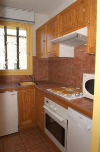 une cuisine avec des armoires en bois et un four blanc dans l'établissement Bouton d or, à Bolquère-Pyrénées 2000 30 autres photos
