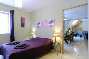 a bedroom with a purple bed and a dining room at Cecile in Montgaillard