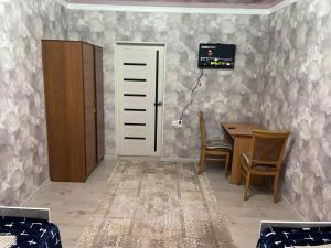 een kamer met een bureau, een tafel en een deur bij Nur Hotel in Karakol