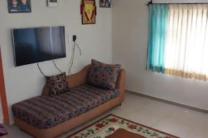 een woonkamer met een bank en een flatscreen-tv bij Aarroh villa in Coonoor