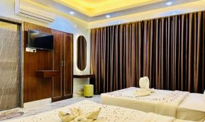 une chambre d'hôtel avec deux lits et une télévision dans l'établissement Cloudy Inn Resort, à Bāndarban
