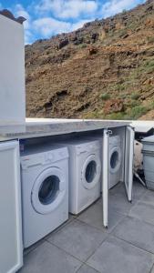 Deux machines à laver sont posées sous un comptoir. dans l'établissement Billy's Marina 360 with pool access, à Puerto de Mogán