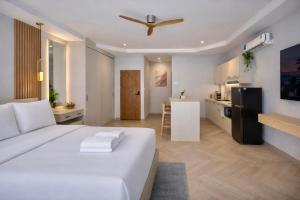 a bedroom with a large white bed and a kitchen at The Escape Kamala in Kamala Beach