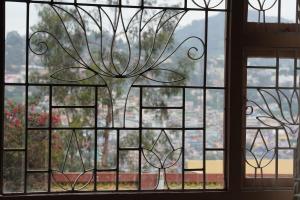 een raam met uitzicht op een boom bij Aarroh villa in Coonoor