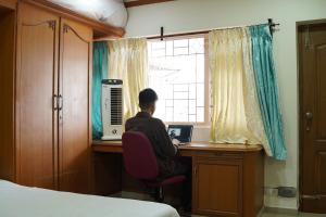a person sitting at a desk with a laptop at Aarroh villa in Coonoor