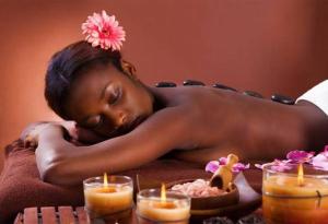 een vrouw die op een bed ligt naast kaarsen bij Jura Nature in Saint-Claude