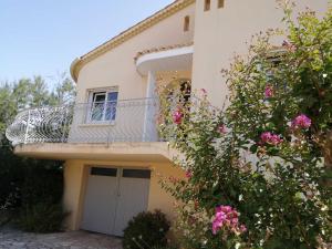 een huis met een balkon en roze bloemen bij Louisiane in Sauvian