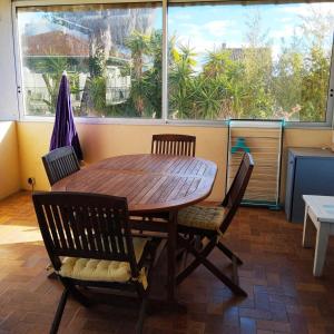een houten tafel en stoelen in een kamer met een raam bij Louisiane in Sauvian +9 foto's