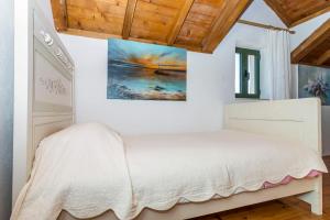 a bedroom with a white bed and wooden ceilings at House Dobrila in Igrane +18 photos