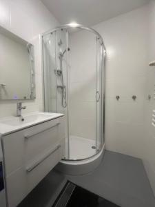 a white bathroom with a shower and a sink at Pokoje Metro Imielin in Warsaw