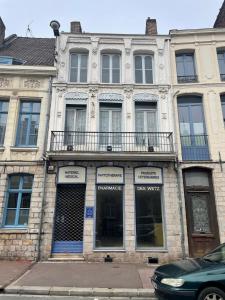 un vieil immeuble avec un balcon sur une rue dans l'établissement Capsule Tattoo Love, à Douai