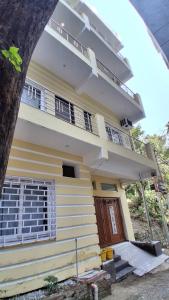 a yellow house with a balcony and a tree at WoodsPicker in Rishīkesh