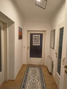 a hallway with a rug and a door with a sign at Juls garden apartment in Tulln