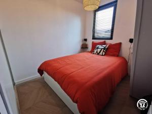 een slaapkamer met een bed met rode lakens en een raam bij Copatito in Cap d'Agde