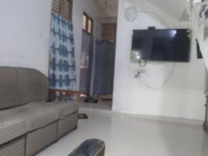 a living room with a couch and a flat screen tv at Orchids Nest Vila Tg in Tangalle