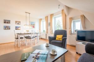 een woonkamer met een tafel en een televisie en een eetkamer bij Haus Decker, App 3 in Wenningstedt