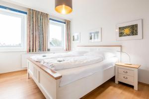 een groot wit bed in een kamer met een raam bij Haus Decker, App 3 in Wenningstedt