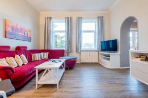 a living room with a red couch and a tv at Haus Decker, App 2 in Wenningstedt