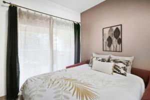 een slaapkamer met een bed met een groot raam bij T2 moderne avec piscine, terrasse et parking privé in Uzès