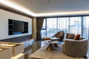 a living room with a television and a couch and chairs at Marquis Hotel in Ban Bang Toei (1)