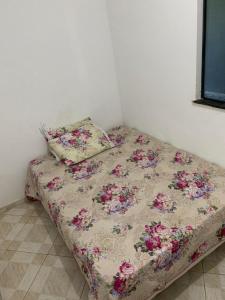 a bed in a room with a floral comforter and a pillow at Casa para Reveillon - cururupe in Ilhéus