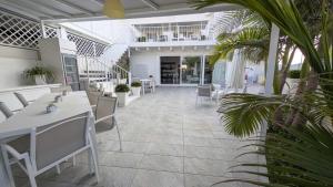 a restaurant with white tables and chairs and palm trees at Casa Lu Salentu - Monolocale superior in Torre Lapillo