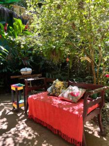 a bed with a red blanket sitting in a garden at Pousada Magia da Mata in Trindade