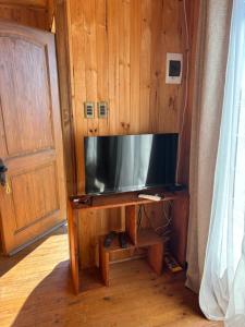 una grande TV a schermo piatto su una parete di legno di Cabañas Vitalis a Curanipe