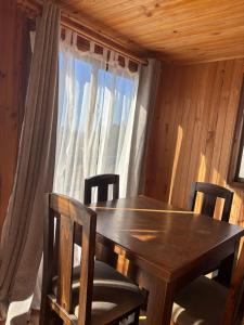 een houten tafel en stoelen in een kamer met een raam bij Cabañas Vitalis in Curanipe