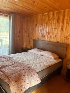 een slaapkamer met een bed met een houten muur bij Cabañas Vitalis in Curanipe