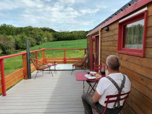 un homme assis à une table sur une terrasse en bois dans l'établissement La roulotte du tonnelier, à Castelnau-de-Montmiral