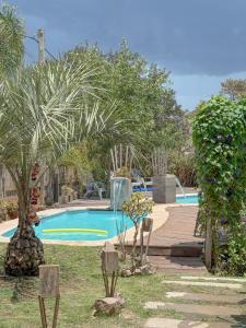 a swimming pool with a palm tree and a fountain at Mandalas de Mar in Punta Del Diablo +23 photos