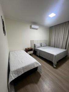 een slaapkamer met twee bedden en een raam bij Pousada Village da Praia in Guarapari