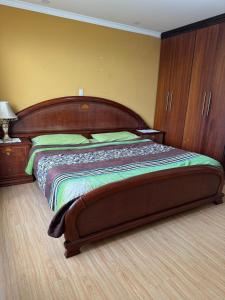 een slaapkamer met een groot bed met een houten hoofdeinde bij Apartamento Cómodo cerca del centro in Loja