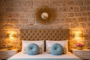a bedroom with a stone wall and a bed with blue pillows at Dominus Rooms in Dubrovnik
