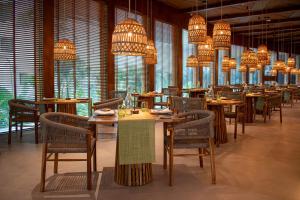 a dining room with tables and chairs and chandeliers at Hotel NYX Cancun in Cancún
