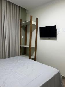 een slaapkamer met een bed en een flatscreen-tv bij Pousada Village da Praia in Guarapari