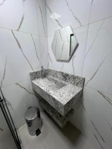 een badkamer met een marmeren wastafel en een spiegel bij Pousada Village da Praia in Guarapari