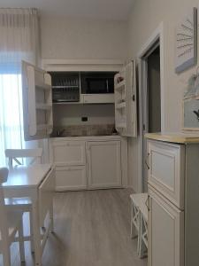 a kitchen with white cabinets and a table and chairs at Mondial Beauty Suite in Bellaria-Igea Marina