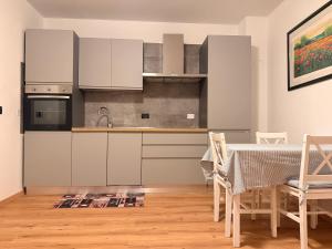 une cuisine avec des armoires blanches et une table avec des chaises dans l'établissement Monolocale a Molveno, à Molveno