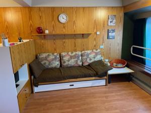 a couch in a room with a clock on the wall at Appartamenti Vacanze Casa -Residence Albare - check in Vacanze Casa - Marilleva 900 in Marilleva