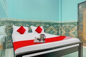 ein Schlafzimmer mit einem Bett mit roten und weißen Kissen in der Unterkunft Hotel O B K Brothers in Gulzārbāgh