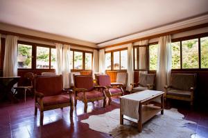 a room with chairs and a table and windows at Hotel Las Cascadas in La Cumbrecita